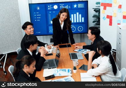 Confidence and young asian businesswoman give presentation on financial business strategy in dashboard report display on screen to colleagues in conference room meeting as harmony in workplace concept. Businesswoman give presentation on dashboard data on screen at harmony office.