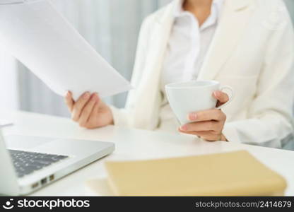 Confidence woman concept, Businesswoman drinking coffee and reading financial data on document.