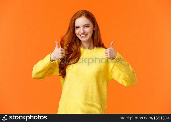 Confident and caring good-looking redhead sister rooting for sibling, saying yes, approving choice, recommend product, show thumbs-up and nod acceptance, smiling positive reply, orange wall.. Confident and caring good-looking redhead sister rooting for sibling, saying yes, approving choice, recommend product, show thumbs-up and nod acceptance, smiling positive reply, orange wall