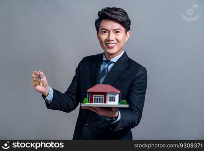 Confident Asian businessman holding house model, advertising home loan with smile. Real estate agent with sample house model in hand on isolated background for housing business advertisement. Jubilant. Confident Asian businessman holding house model. Jubilant