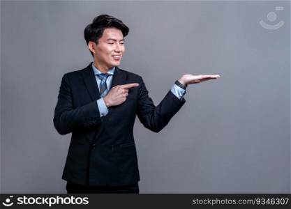 Confident Asian businessman posing in professional outfit on isolated background. Office worker make hand holding gesture for product sales promotions advertisements or HR recruitment image. Jubilant. Businessman make hand holding gesture for advertisements. Jubilant