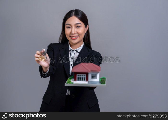 Confident Asian businesswoman holding house model, advertising home loan with smile. Real estate agent with sample house model in hand on isolated background for business advertisements. Jubilant. Confident Asian businesswoman holding house model. Jubilant