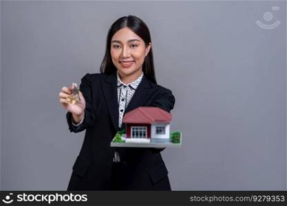 Confident Asian businesswoman holding house model, advertising home loan with smile. Real estate agent with sample house model in hand on isolated background for business advertisements. Jubilant. Confident Asian businesswoman holding house model. Jubilant
