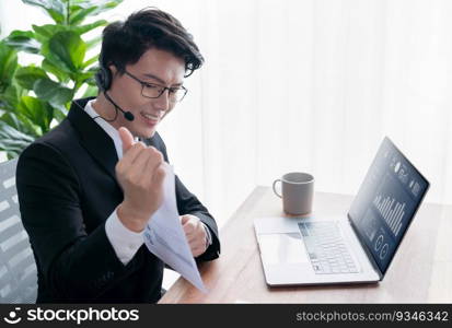 Confident asian telesales businessman work in modern office wearing headphone, presenting BI dashboard analysis to clients and customers in online meeting. Success modern telesales business . Jubilant. Asian telesales businessman work in office wearing headphone. Jubilant