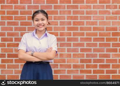 Confident Asian Woman Student  Arm Crossed uniform happy smile with brick wall copy space.