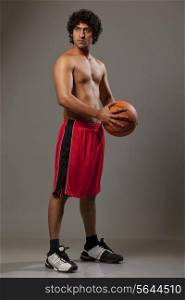 Confident basket ball player standing over grey background