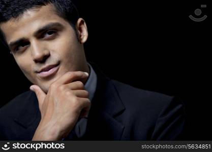Confident business man with hand on chin over black background