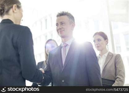 Confident business partners shaking hands in office