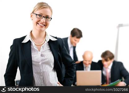 Confident business woman standing in front of her colleagues; selective focus on woman