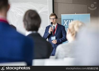 Confident businessman giving presentation to audience in seminar hall