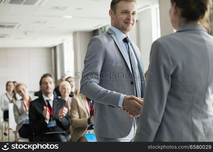 Confident businessman greeting public speaker during seminar