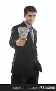 Confident businessman holding Indian currency over white background