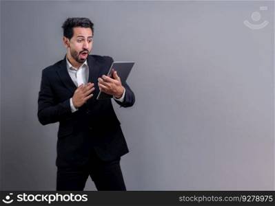 Confident businessman in formal suit holding tablet with surprise look for promotion or advertising. Facial expression and gestures indicate excitement and amazement on an isolated background. Fervent. Confident businessman in formal suit holding tablet with surprise look. Fervent