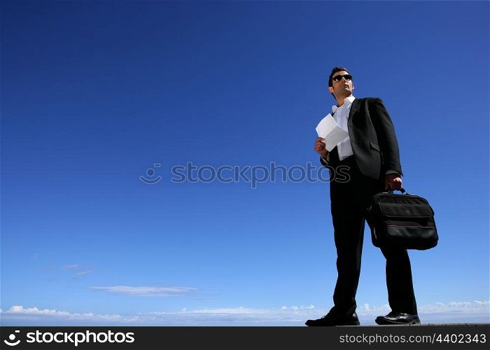 Confident businessman in front of blue sky