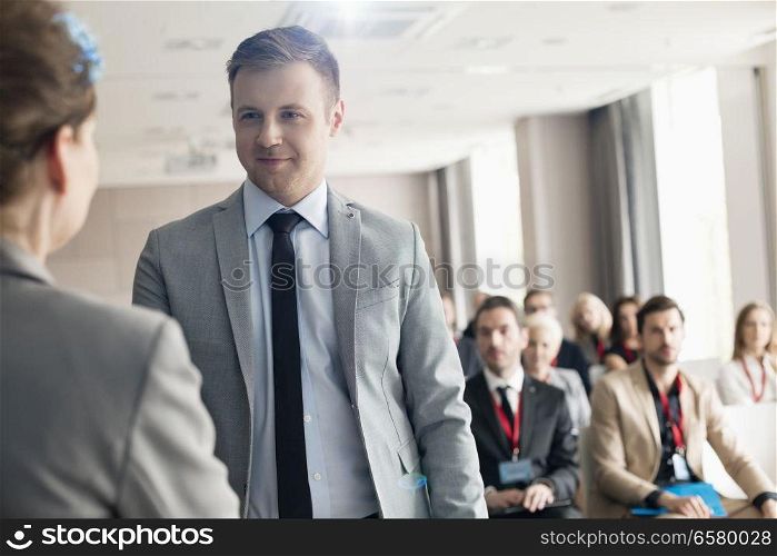 Confident businessman looking at public speaker during seminar