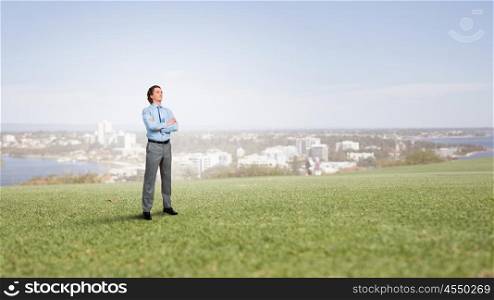 Confident businessman outdoors. Businessman standing on green grass with his arms crossed