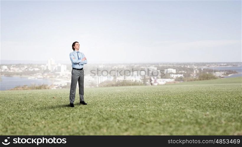 Confident businessman outdoors. Businessman standing on green grass with his arms crossed