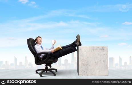 Confident businessman. Smiling businessman sitting in chair with legs on table