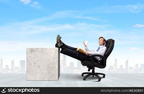 Confident businessman. Smiling businessman sitting in chair with legs on table