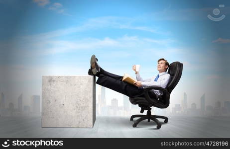 Confident businessman. Smiling businessman sitting in chair with legs on table