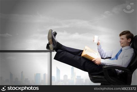 Confident businessman. Smiling businessman sitting in chair with legs on table