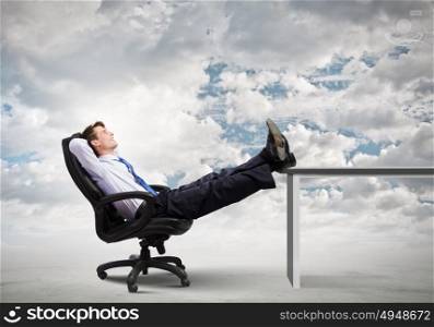 Confident businessman. Smiling businessman sitting in chair with legs on table