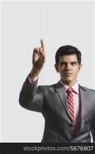 Confident businessman touching visual screen against white background