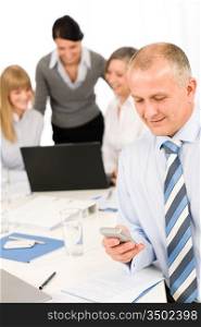 Confident businessman use phone during meeting with team colleagues