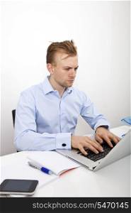 Confident businessman using laptop at desk in office