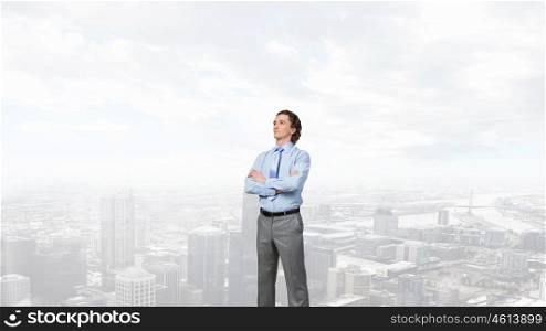 Confident businessman with arms crossed on chest against modern city view