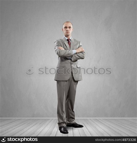 Confident businessman. Young successful handsome businessman in suit in empty room