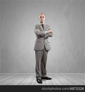 Confident businessman. Young successful handsome businessman in suit in empty room
