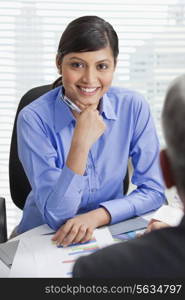 Confident businesswoman smiling with male executive in office