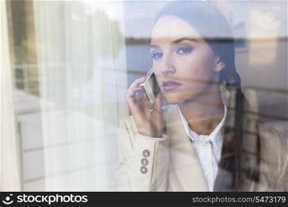 Confident businesswoman using cell phone in office