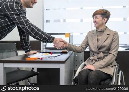 confident businesswoman wheelchair shaking hands