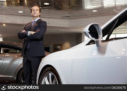 Confident car salesperson standing with arms crossed