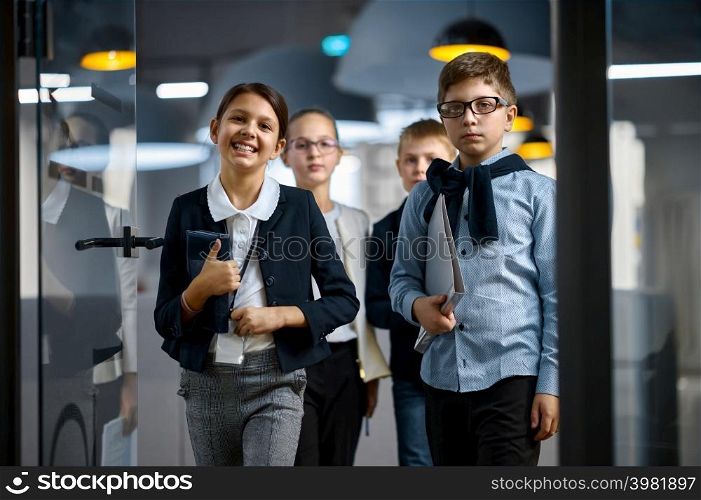 Confident children business group entering office looking at camera. Creative office workers team. Diverse confident children business group entering office