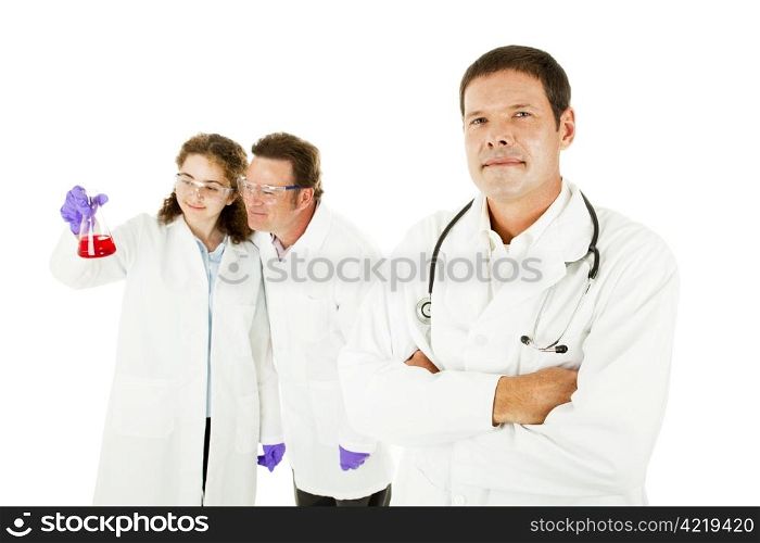Confident doctor with two lab assistants in the background. Isolated on white.