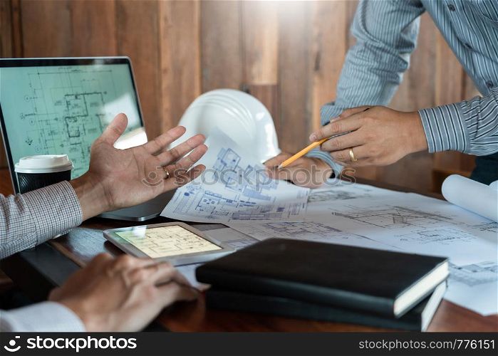 Confident engineer team working with Blue Print with architect equipment discussing and Planning work flow construction project. with partner at the table in office work site.