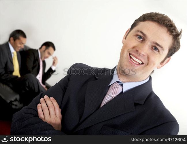 confident european business man in an office with some businesspeople in the background