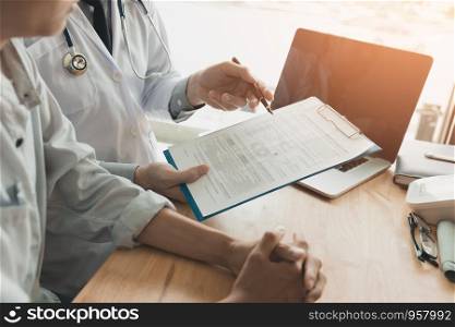 Confident female doctor reviews patient medical information and pointing to medical forms.