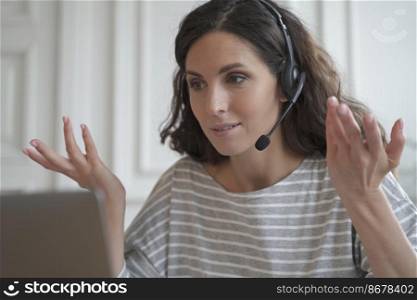 Confident focused young spanish businesswoman wearing wireless headphones having video call conversation with partner or giving professional consultation, consulting customer online. Young spanish businesswoman wearing wireless headphones consulting client online