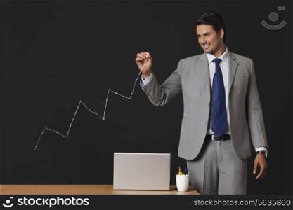 Confident Indian businessman drawing graph on transparent screen at office
