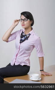 Confident Indian businesswoman sitting on office desk