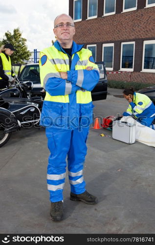 Confident looking paramedic posing for the camera in front of a car crash