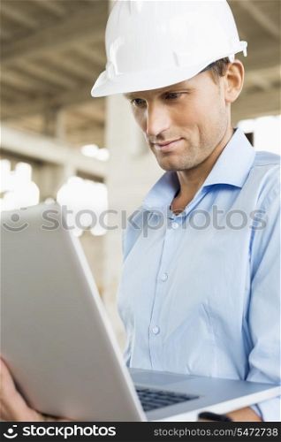 Confident male architect using laptop at construction site