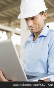 Confident male architect using laptop at construction site