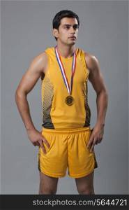 Confident male winner with hands on hip looking away over gray background
