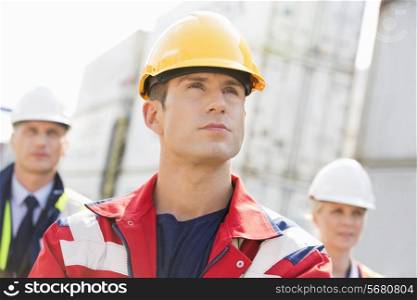 Confident male worker with colleague in background at shipping yard