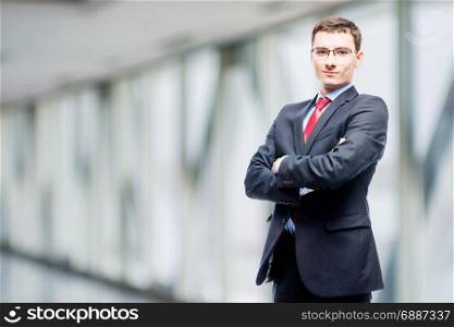 Confident manager in suit posing against in office